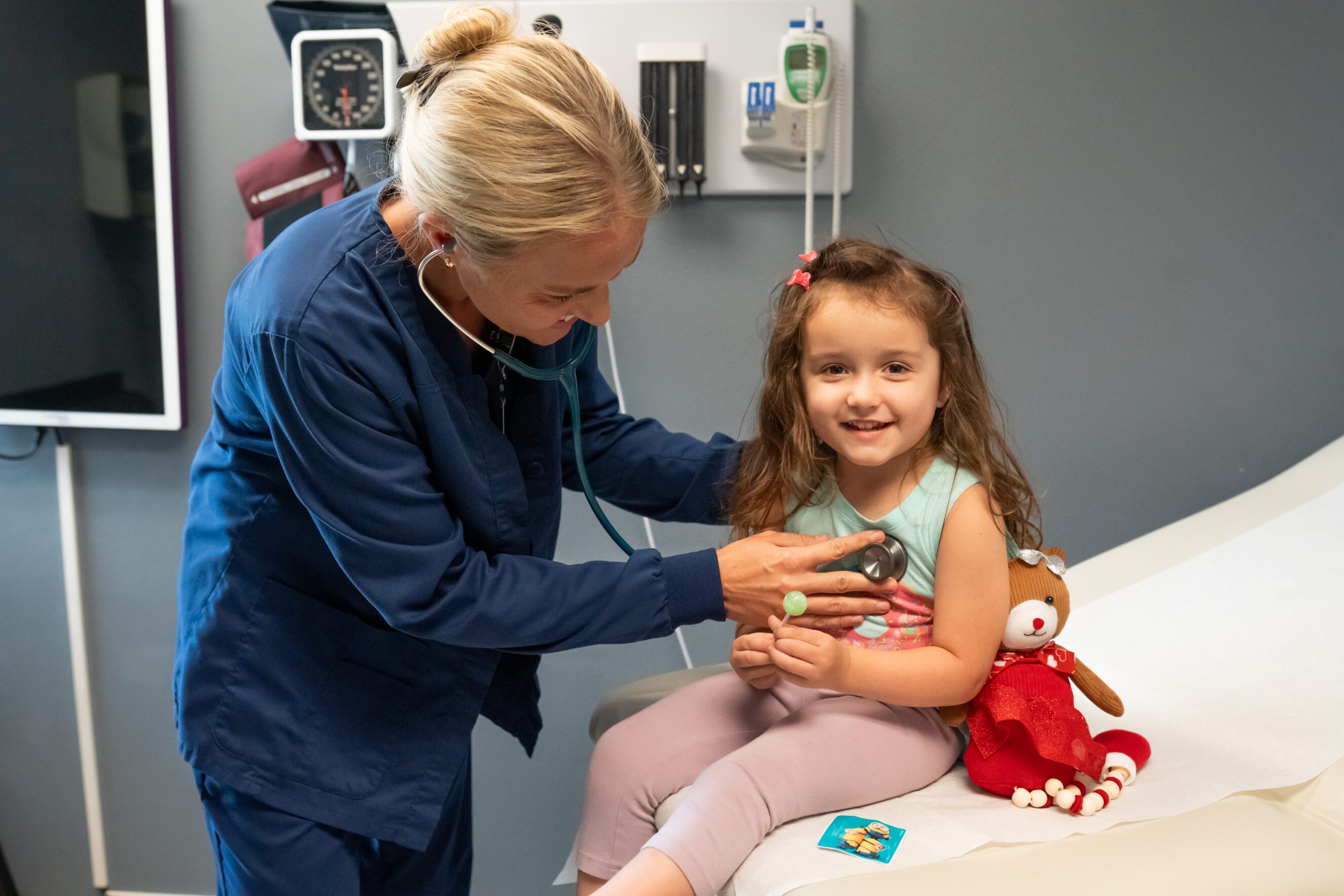 nurse listening to smiling child’s heartbeat during walk-in clinic visit